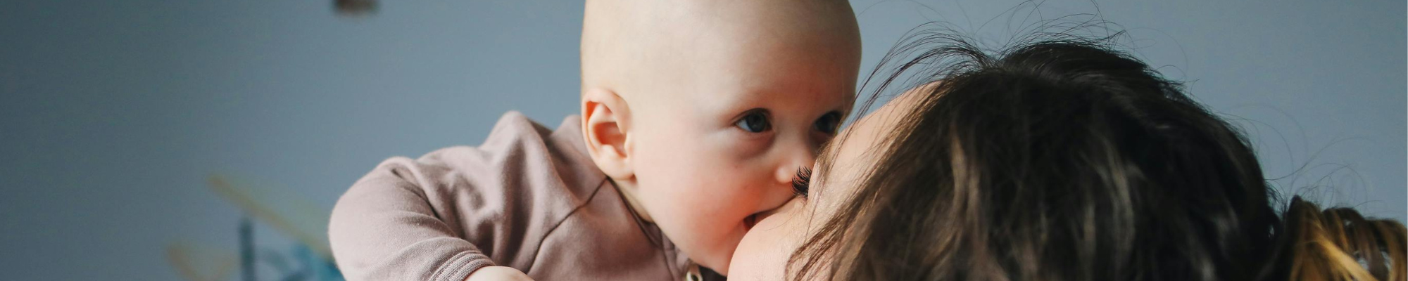 Maman qui porte son bébé et lui fait un bisous